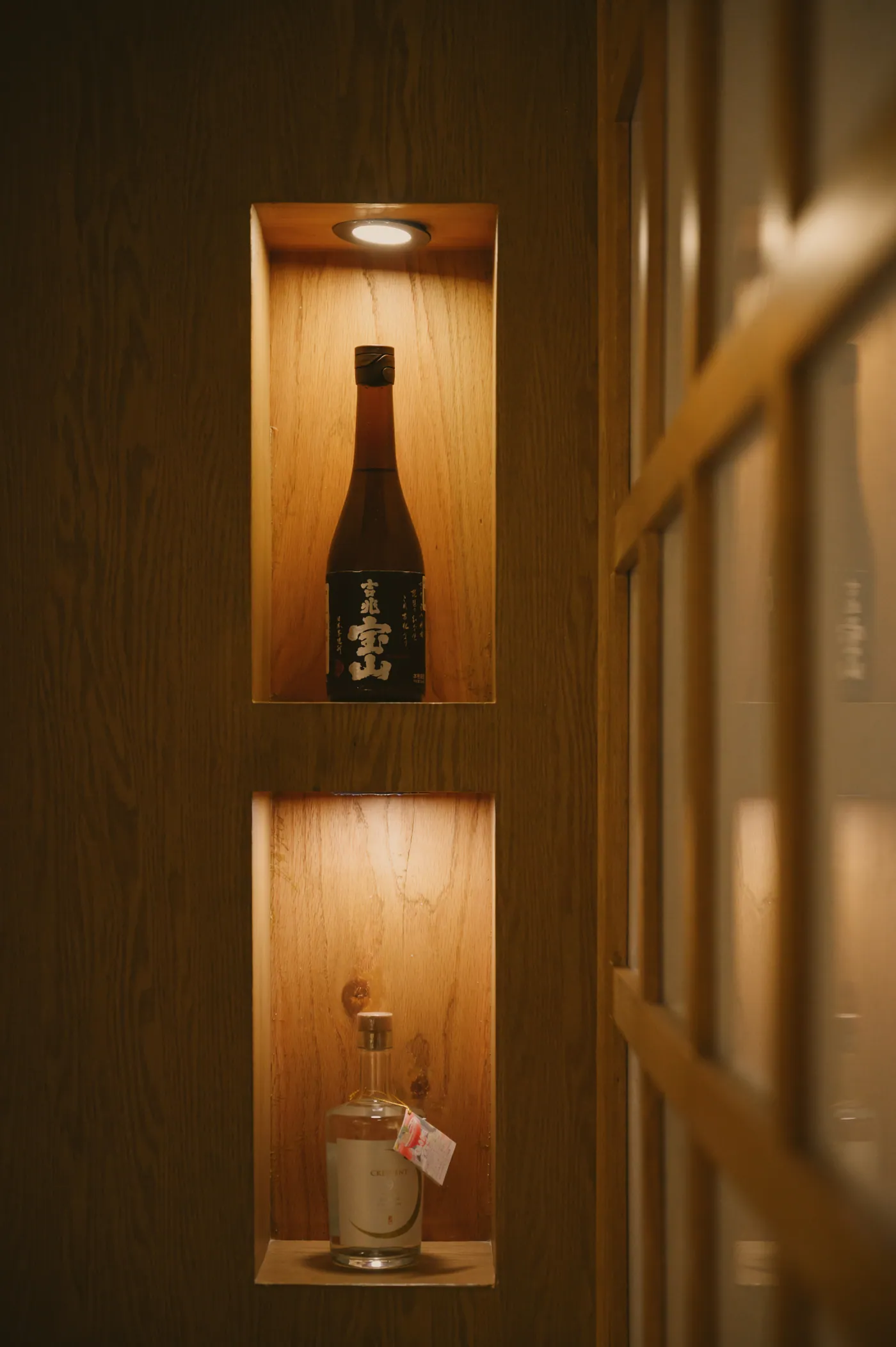 Botellas de sake japones premium en los nichos iluminados del bar de Torobi