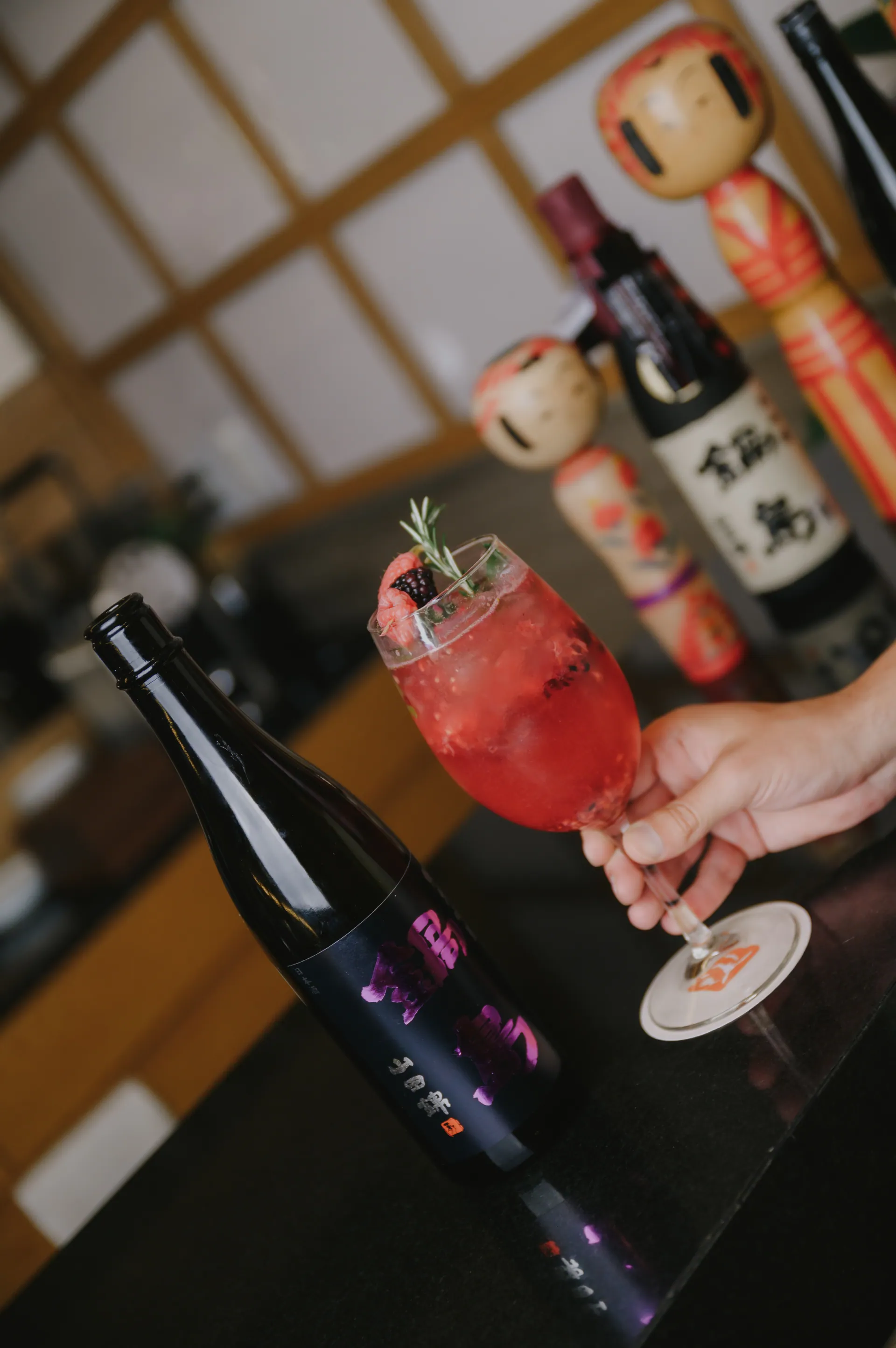 Sake y coctel de berries en la barra de Torobi, con kokeshi dolls japonesas