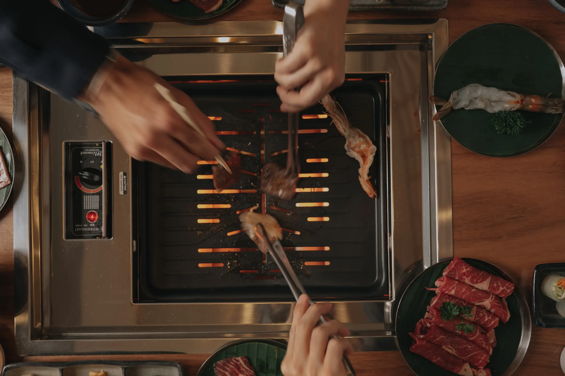 Parrilla japonesa a fuego lento en Torobi Polanco, vista desde arriba con cortes premium y comensales cocinando
